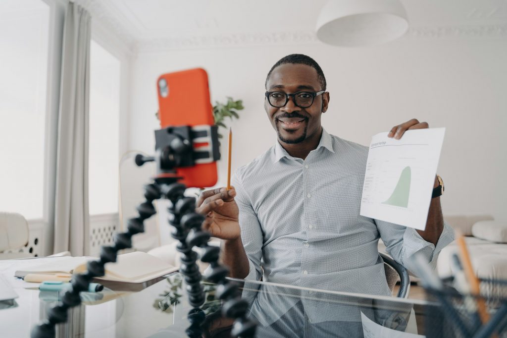 African american businessman shows economic statistics, consulting client by video call, using phone