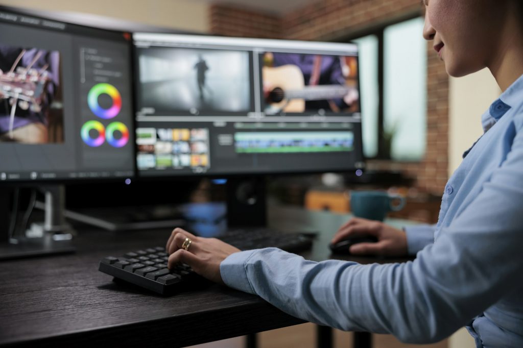 Close up shot of professional videographer sitting at desk while enhancing movie footage