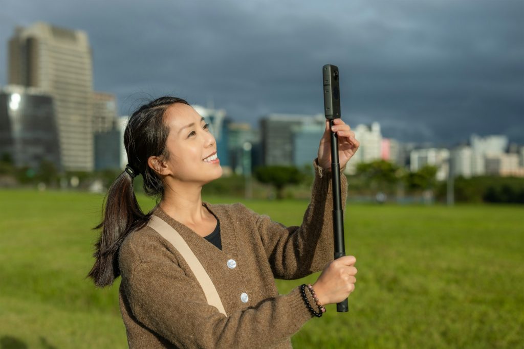 Woman use 360 digital camera to take photo in park